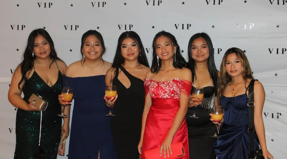 Sei studentesse del Como Secondary College posano eleganti davanti a uno sfondo VIP.