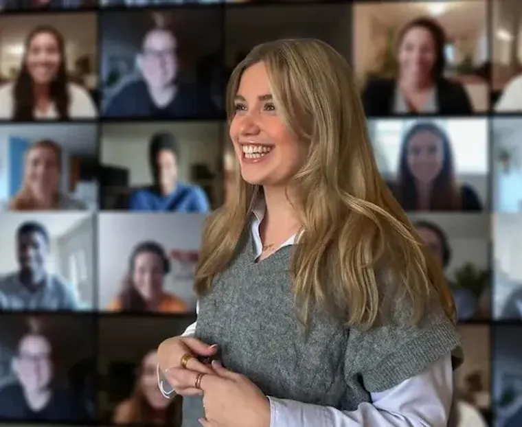 Donna sorridente durante una videochiamata con una griglia di partecipanti collegati online