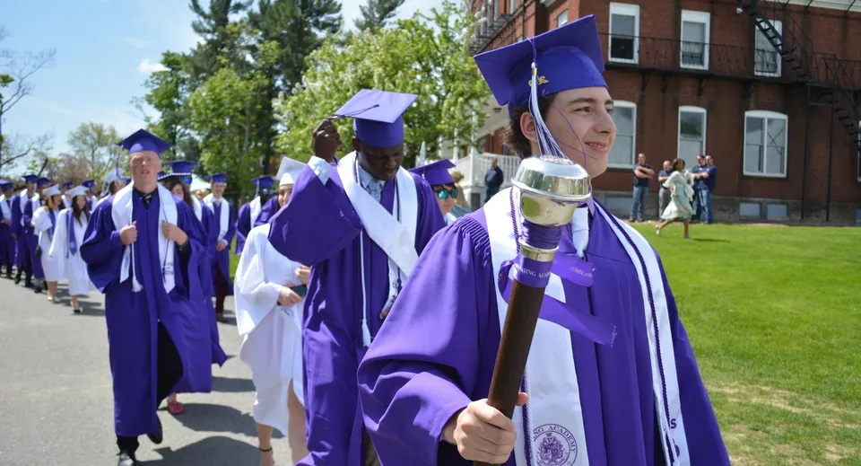 Neodiplomati in toga viola e tocco camminano nel campus della Cushing Academy.
