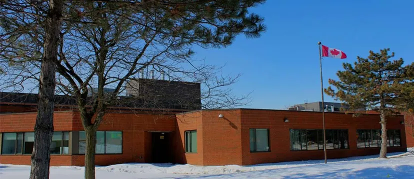 L'edificio in mattoni dell'Albert Campbell Collegiate Institute in una giornata di neve con la bandiera canadese e alberi sullo sfondo.