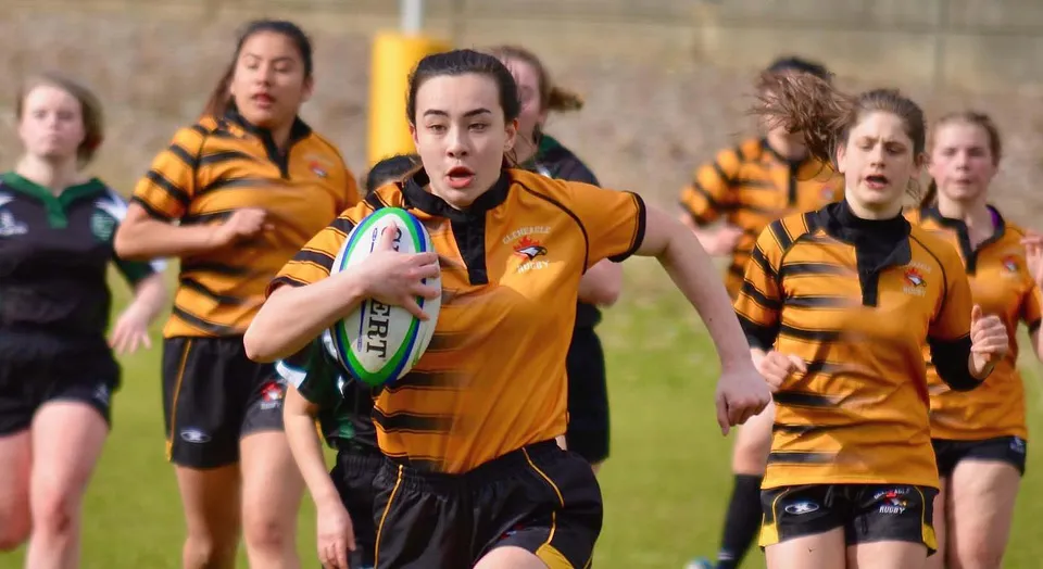 Un gruppo di giocatrici di rugby corre sul campo della Gleneagle Secondary School.