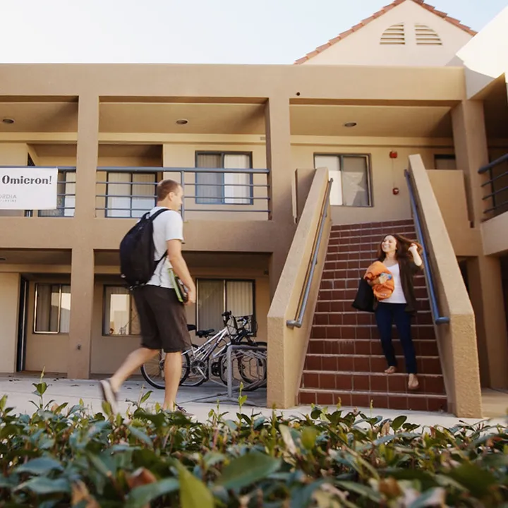 Estudiantes ante un edificio de la residencia del campus con escalera exterior y bicicletas aparcadas