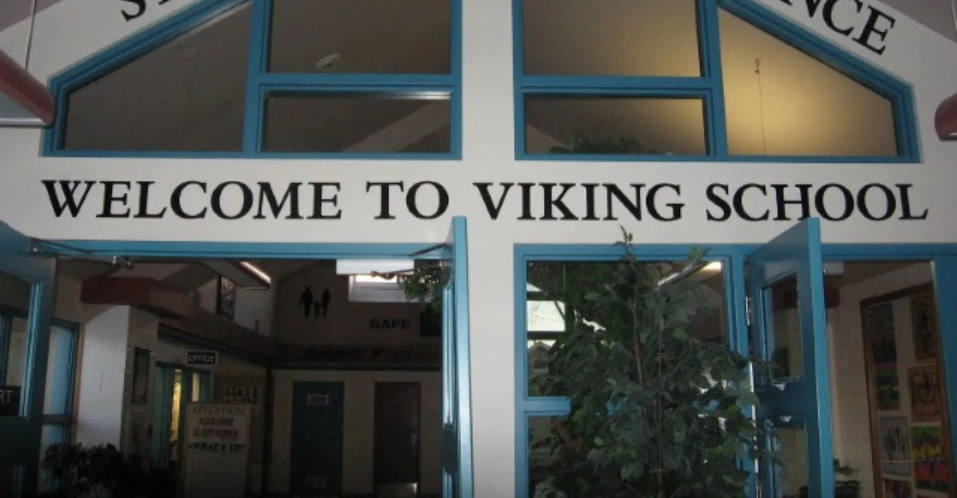 L'ingresso della Viking School con un grande cartello di benvenuto sopra la porta e una vista sul corridoio attraverso le vetrate.