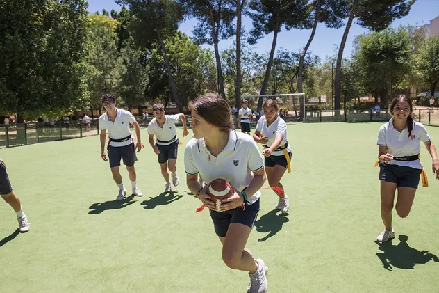 Schülerinnen und Schüler beim Ballspiel auf dem Sportplatz einer Schule in Spanien