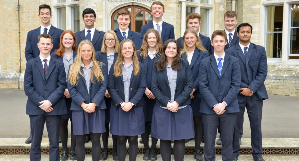 Un gruppo di studenti della Canford School in abito formale davanti a un edificio storico.