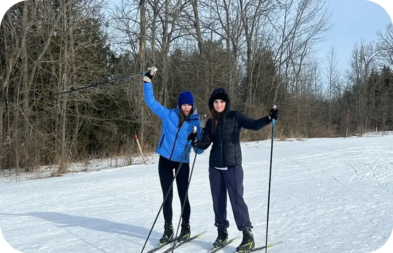 Due ragazze fanno sci di fondo su una pista innevata al limitare di un bosco