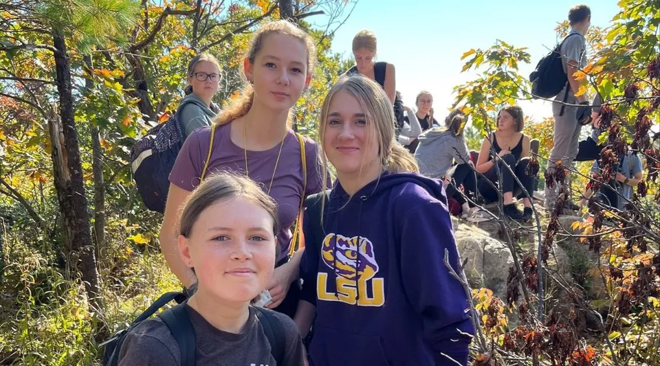 Un gruppo di studentesse del Smiths Falls District Collegiate Institute si trova in un'area boschiva autunnale.