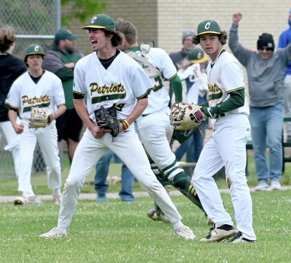 Un gruppo di giocatori di baseball in divisa bianca e verde sta sul campo da gioco della Coventry High School.