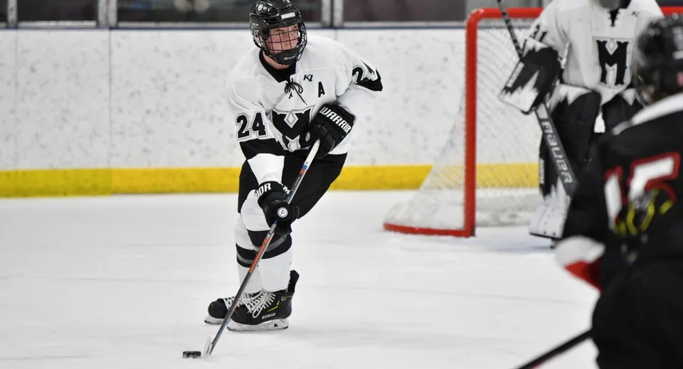 Un giocatore di hockey con maglia bianca e pantaloni neri gioca sul ghiaccio nel terreno della Phoenix Magnet Academy.