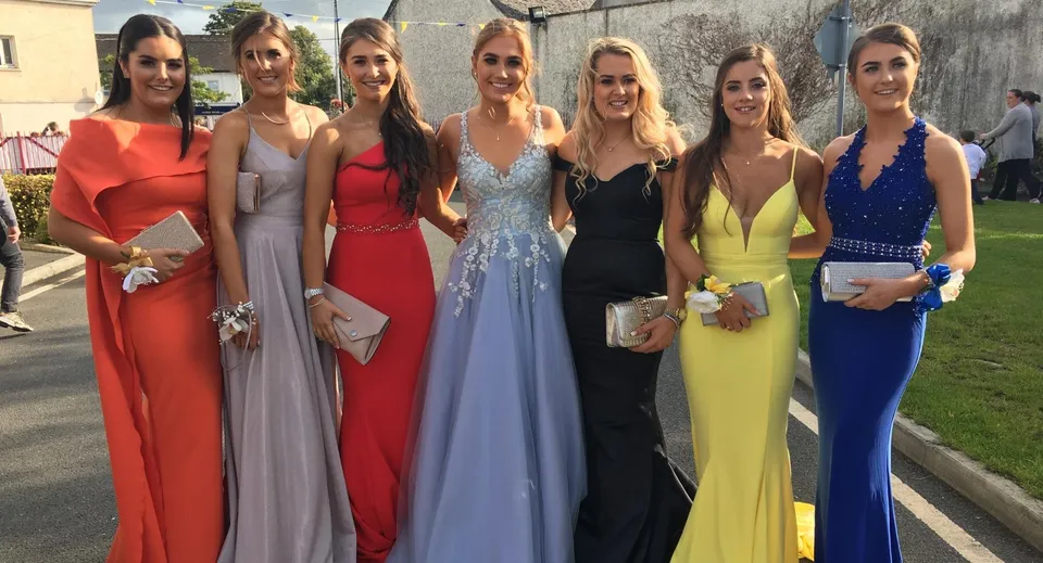 Un gruppo di giovani donne in abiti formali posa all'esterno davanti a un edificio nel campus della Presentation Secondary School Kilkenny.