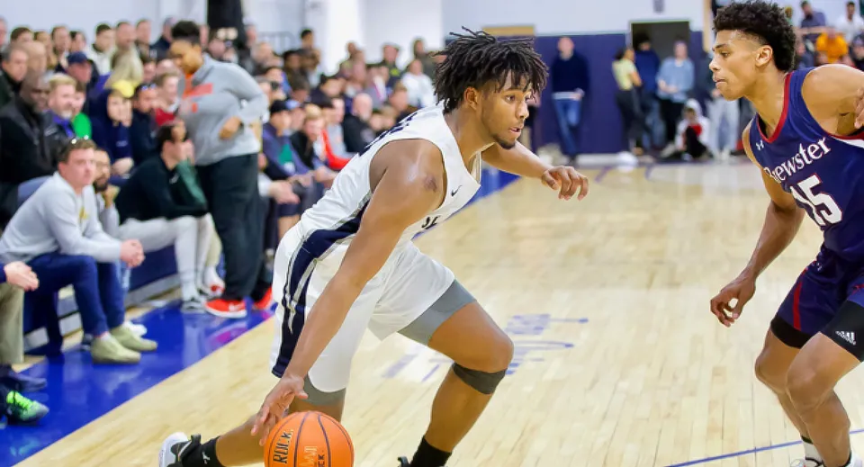 Un giocatore di pallacanestro della St. Thomas More School palleggia durante una partita in palestra.