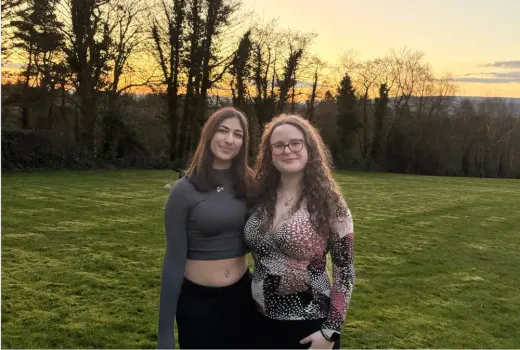 Zwei Mädchen posieren bei Sonnenuntergang auf einer Wiese in Irland