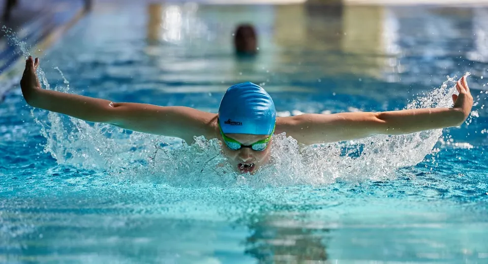 Una studentessa della Sherborne Girls' School nuota in piscina tra gli schizzi d'acqua.