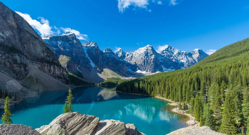Un calmo lago di montagna turchese davanti a cime innevate e foreste sempreverdi nel terreno dell'Appleby College.