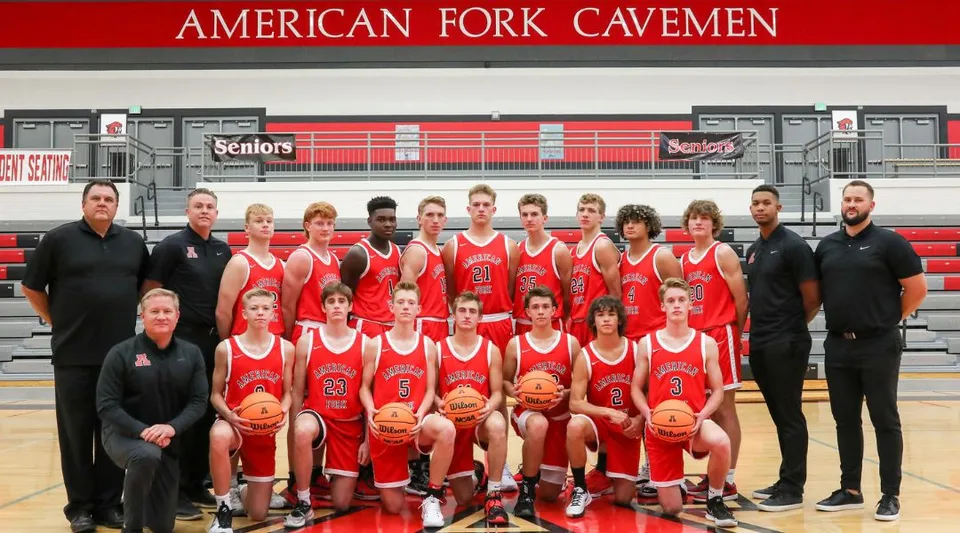 La squadra di basket dell'Alpine School District posa in divisa rossa davanti a uno striscione con la scritta American Fork Cavemen.