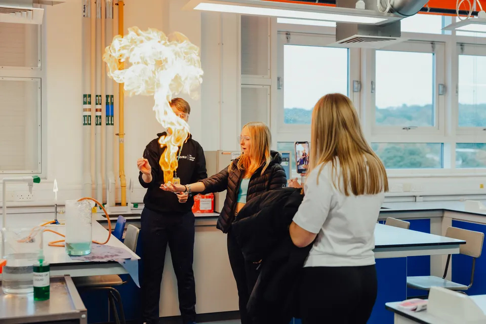 Studenti di The Sheffield College osservano una reazione chimica con una grande fiamma in laboratorio.