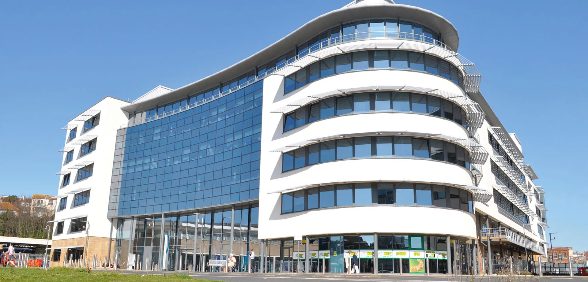 Il moderno edificio a più piani dell'East Sussex College Hastings con facciata in vetro e architettura curva contro un cielo blu.