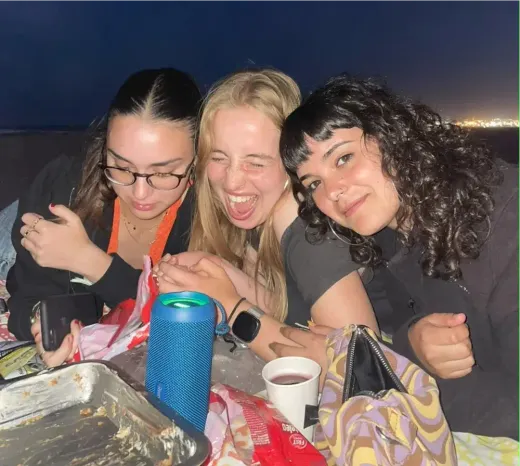 Drei Mädchen lachen bei einem abendlichen Picknick in Spanien