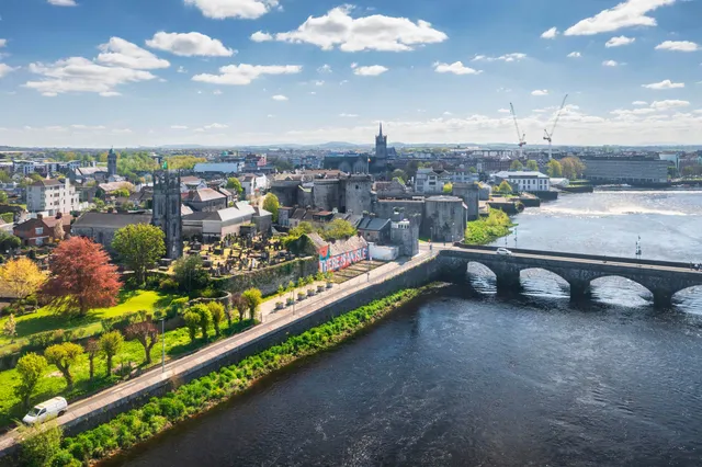 Vista aérea de una ciudad irlandesa a orillas del río con un castillo medieval y un puente de piedra
