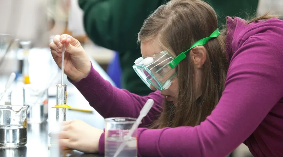 Una studentessa dell'Eugene School District conduce un esperimento scientifico in laboratorio con vari strumenti di vetro.
