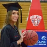 Joven estudiante vestida con toga y birrete sostiene un balón de baloncesto