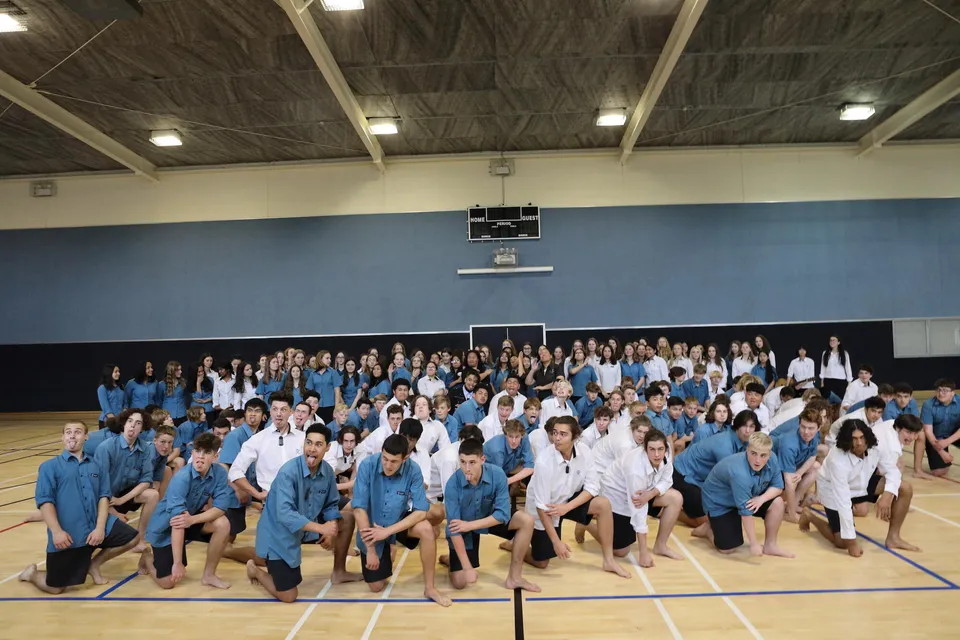 Studenti del Glendowie College in uniforme scolastica posano sul pavimento di una palestra.