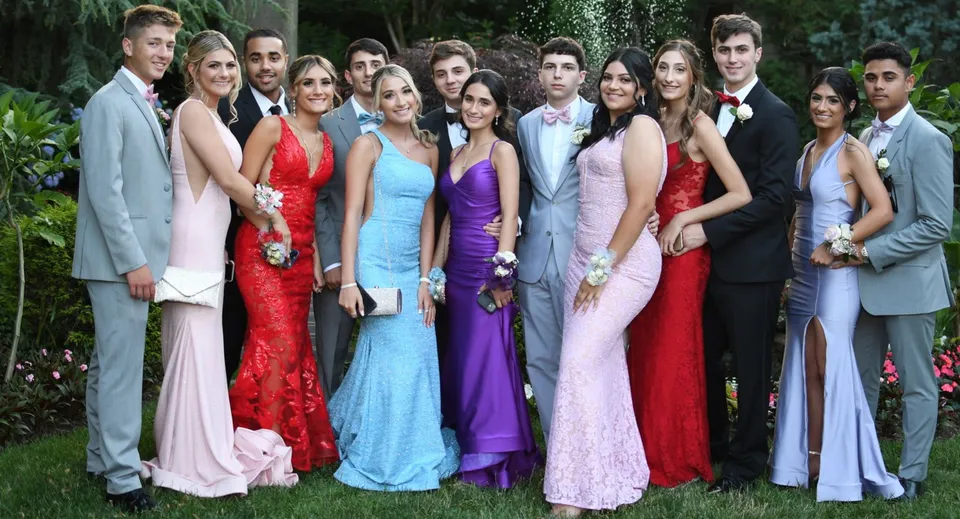 Un gruppo di studenti della Portmarnock Community School posa insieme in abiti formali in giardino.