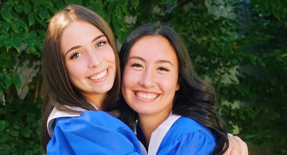 Due studentesse della Reynolds Secondary School sono insieme davanti a uno sfondo verde e sorridono.