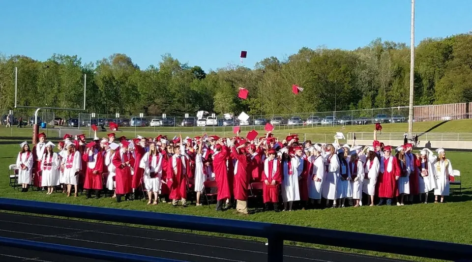 Gli studenti della Lowell High School si radunano sul campo sportivo con toghe rosse e bianche per la loro cerimonia di diploma.