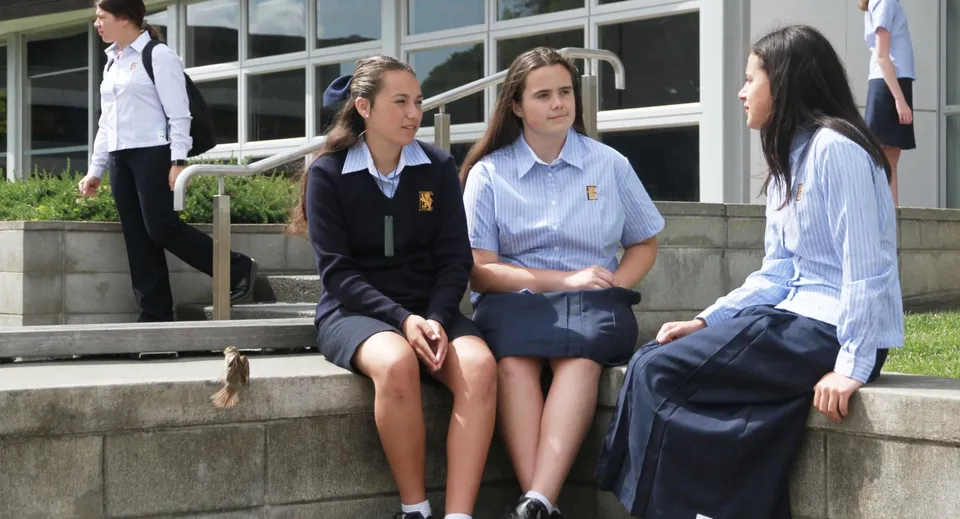 Studentesse della Epsom Girls Grammar School sedute su una scalinata davanti all'edificio scolastico mentre chiacchierano.