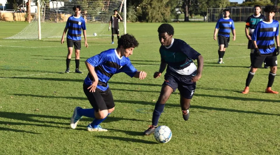 Un gruppo di giocatori di calcio in divisa blu e nera gioca una partita sul campo sportivo del Sevenoaks Senior College.