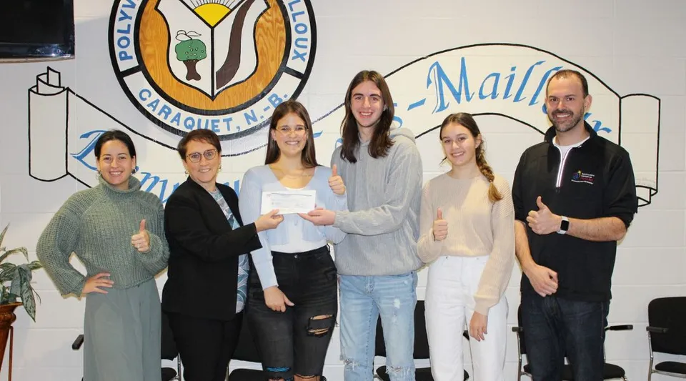 Un gruppo di studenti in piedi davanti a un murale variopinto nel campus della Polyvalente Louis-Mailloux.