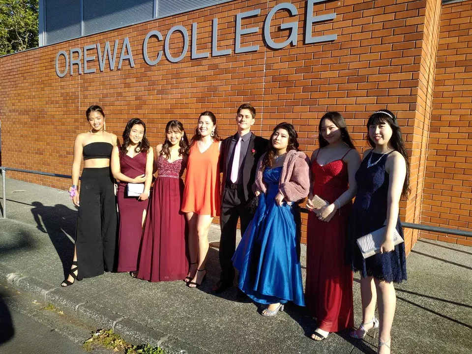 Un gruppo di studenti si trova davanti all'edificio in mattoni dell'Orewa College.