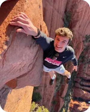 Leif sorride in cima a una parete di roccia rossa negli Stati Uniti.