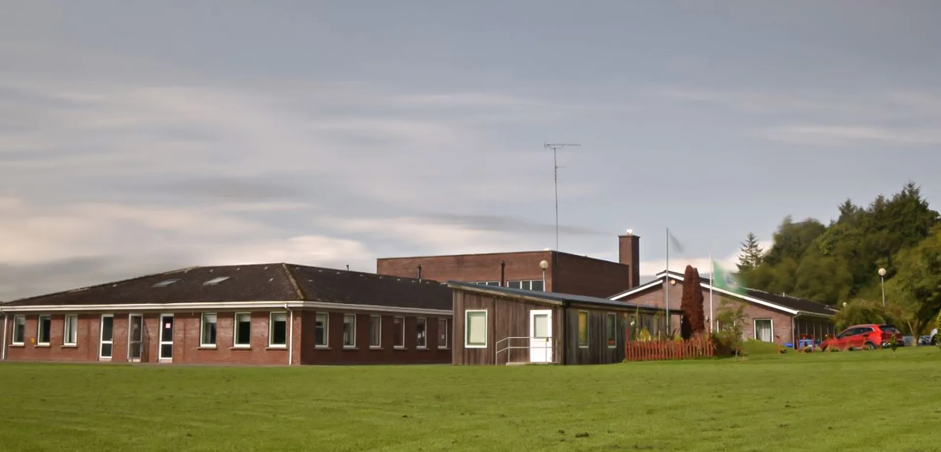 L'edificio scolastico dell'O’Carolan College si trova su un prato ed è circondato da alberi.