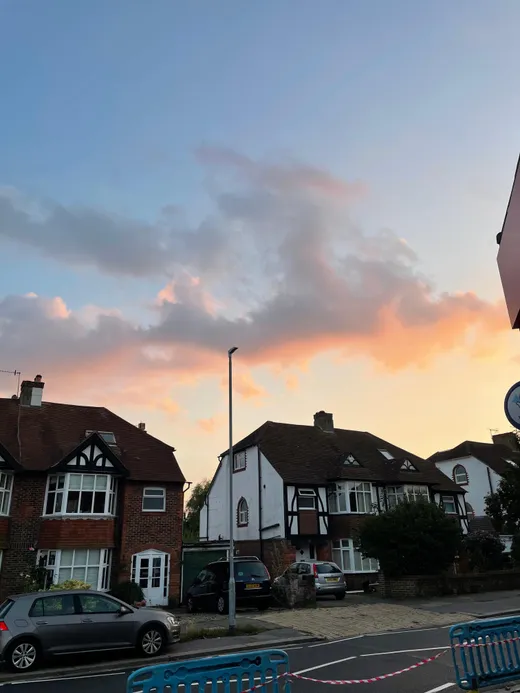 Hilera de casas inglesas con tejados a dos aguas bajo un cielo rosado al atardecer