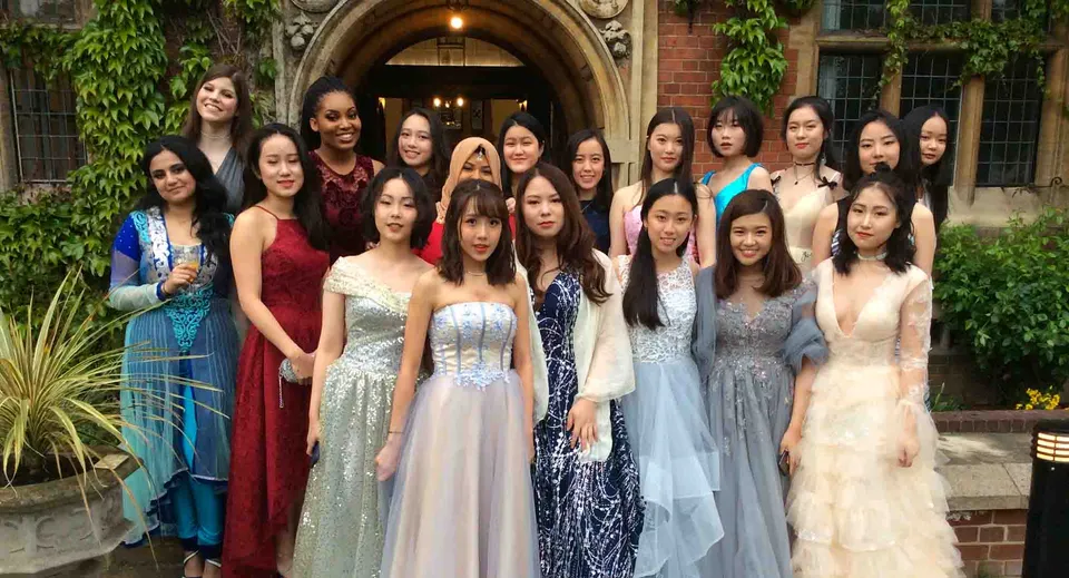Un gruppo di giovani donne in abbigliamento formale davanti allo storico edificio in mattoni della St. Mary's School.