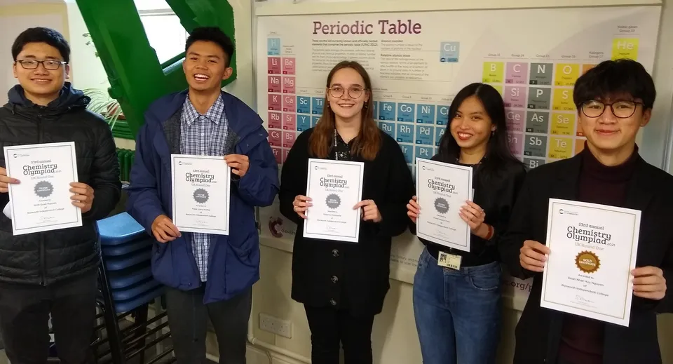 Cinque studenti mostrano degli attestati in un'aula davanti alla tavola periodica nel campus del Bosworth Independent College.