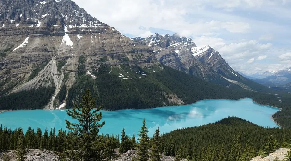 Un lago turchese con montagne innevate sullo sfondo e verdi foreste in primo piano nei pressi del Gander Collegiate.