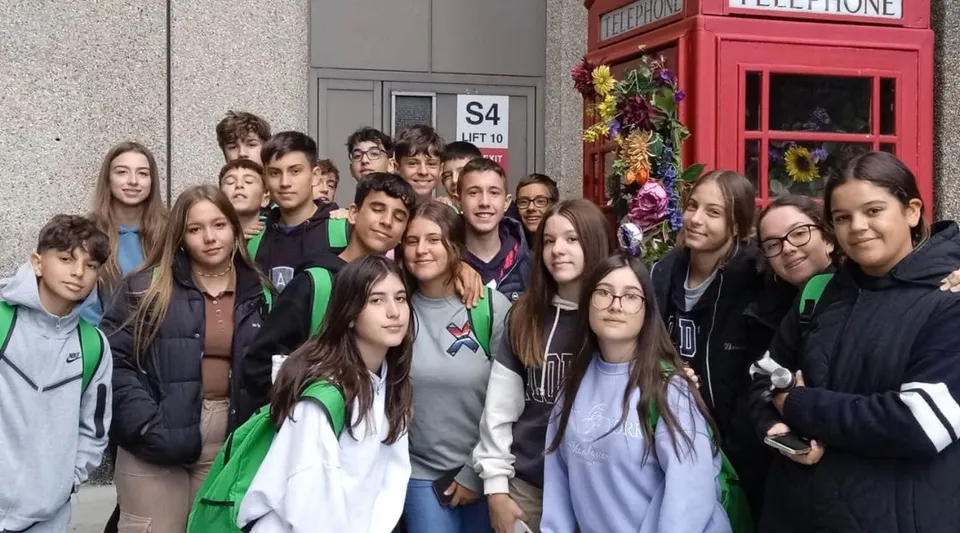 Un gruppo di studenti in divisa verde e bianca si trova davanti a una cabina telefonica rossa nel campus del Colegio Argantonio.