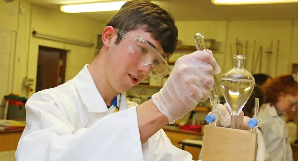 Uno studente della Mercy Secondary School lavora con cura con apparecchiature scientifiche in laboratorio.