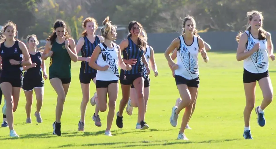 Un gruppo di giovani atlete si allena insieme sul campo sportivo del Manawatu College.