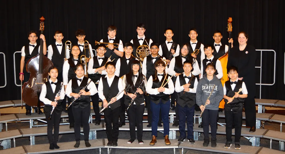 Un gruppo di studenti della Matthew McNair Secondary School sta in abiti formali su un palco davanti a uno sfondo scuro.
