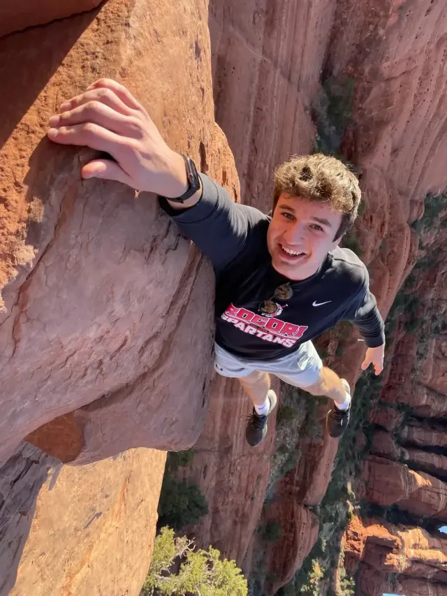 Estudiante sonriente escala una pared de roca roja en Estados Unidos