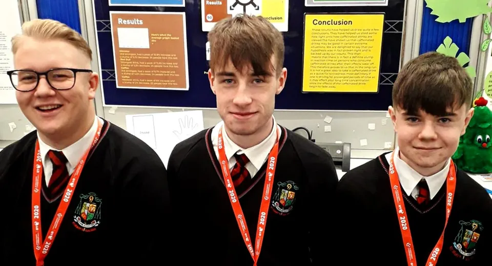 Tre studenti in divisa scolastica sono in piedi davanti a un pannello informativo nel campus del St. Marys College Galway.