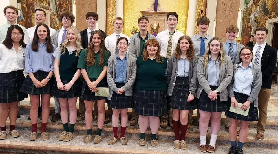 Un gruppo di studenti e studentesse si trova nel corridoio della Nativity BVM High School con un'architettura decorata sullo sfondo.