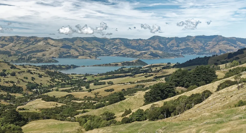 Un paesaggio pittoresco con verdi colline e un lago davanti alle montagne, non direttamente nel campus della Papanui High School.