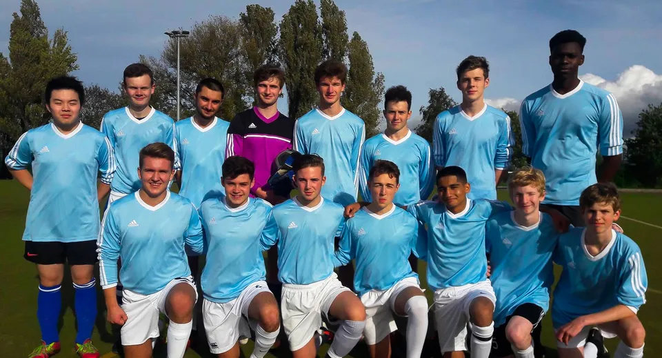 Un gruppo di giovani calciatori posa con la divisa della squadra su un campo nel campus del MPW Cambridge.
