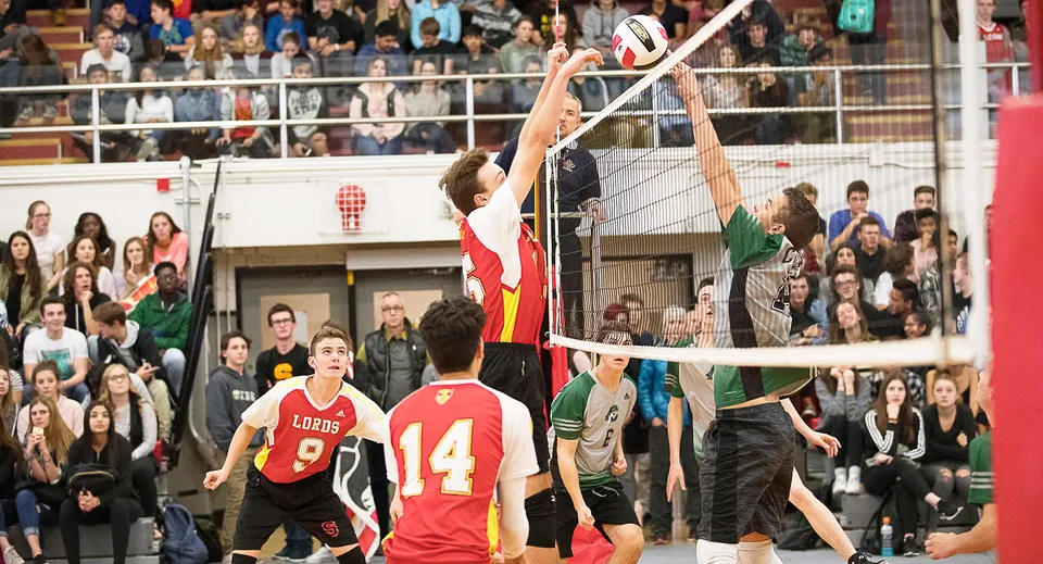 Un gruppo di studenti e studentesse della Strathcona High School gioca a pallavolo davanti al pubblico nella palestra.
