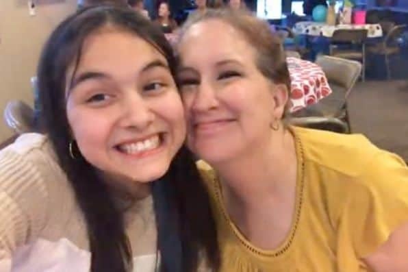 Una chica joven y una mujer con camiseta amarilla se toman un selfi sonriendo juntas